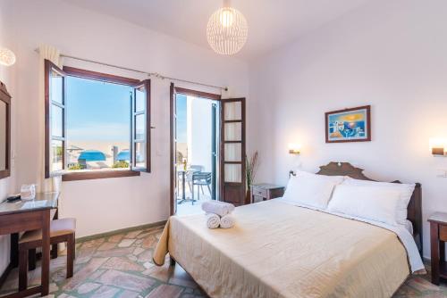 a bedroom with a bed and a desk and windows at Agia Irini in Imerovigli