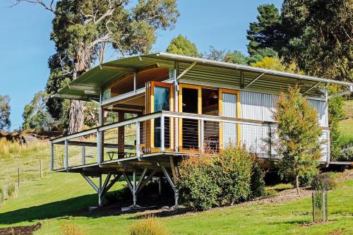 a house with a green roof on a grass field at Hobart Hideaway Pods in Kingston