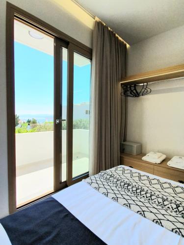 a bedroom with a bed and a large window at St.Thomas Beach Luxury Apartments in Pefki
