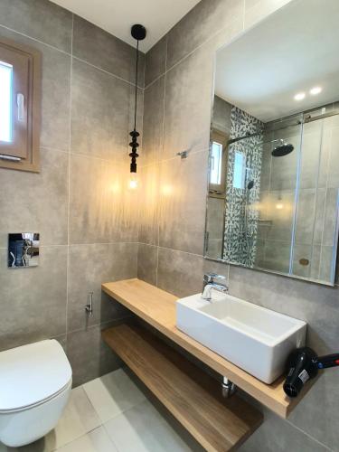 a bathroom with a sink and a toilet and a mirror at St.Thomas Beach Luxury Apartments in Pefki
