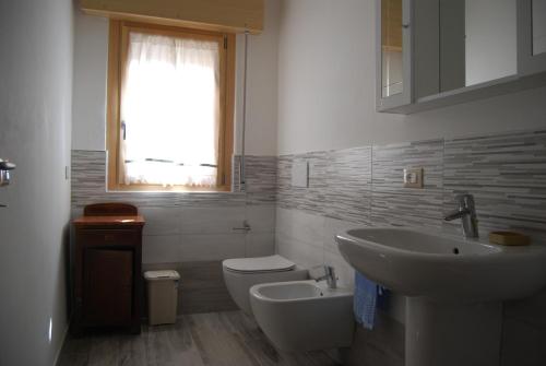 un bagno con lavandino, WC e finestra di CORTE GRAZIA a San Zeno di Montagna