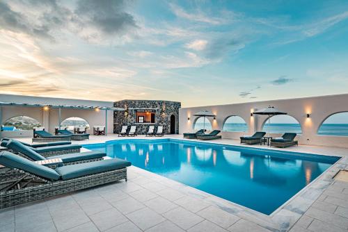 a hotel pool with lounge chairs and the ocean at Agia Irini in Imerovigli