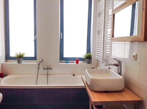 baño con bañera y lavamanos y 2 ventanas en Canal House - Homestay, en Alkmaar