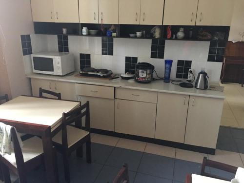 a kitchen with white cabinets and a table and a microwave at Гостевой дом писателей in Odesa