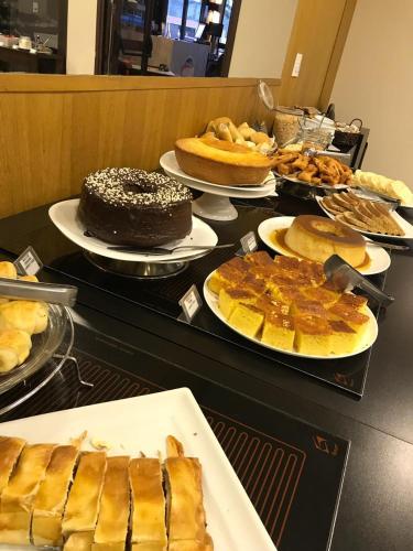 a table with different types of cakes and pies at Hotel Residence Jaguary in Jaguariúna