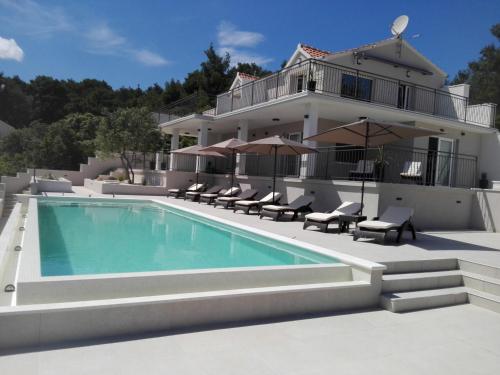 a house with a swimming pool in front of a house at Holiday Hvar in Vrbanj