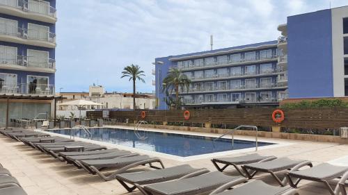 a swimming pool with lounge chairs next to a building at Hotel Cesar Augustus in Cambrils
