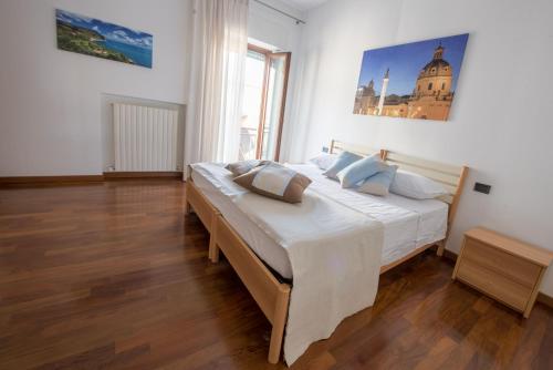 1 dormitorio con 1 cama con sábanas blancas y almohadas azules en Appartamento in completo confort, en Montegranaro