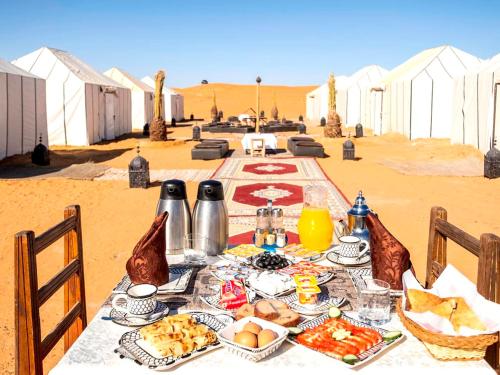 Une table avec de la nourriture dans le désert dans l'établissement Merzouga Luxury Bivouac, à Merzouga