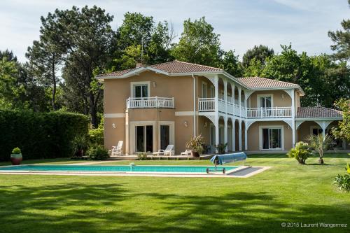 une grande maison avec une piscine dans la cour dans l'établissement LE CLOS D'IGNAC, à Lège-Cap-Ferret