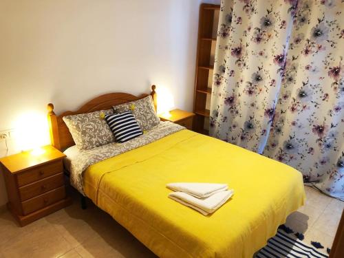 Un dormitorio con una cama amarilla con toallas. en Apartament Lloret de Mar with terrace en Lloret de Mar