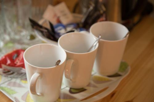 three white cups sitting on a table with a plate at Station House Bed & Breakfast in Ennistymon