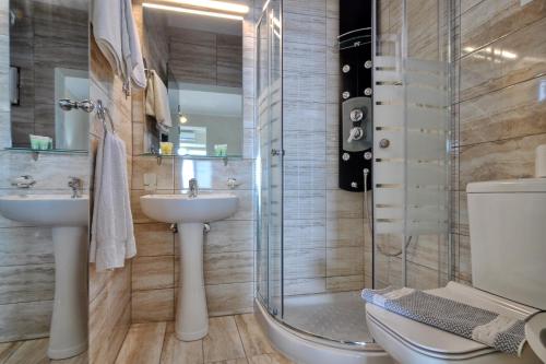a bathroom with a shower and a sink and a toilet at Golden Fox Studios and Suites in Lákones