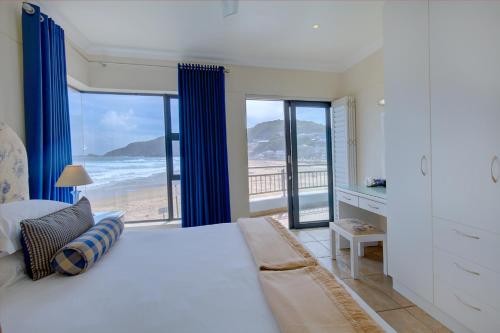 a bedroom with a bed and a view of the beach at Makarios On Sea in Herolds Bay