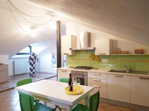 a kitchen with a white table and green chairs at Cascina Bringin in Mondovì