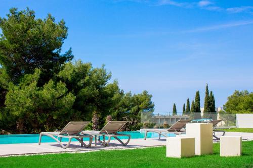 un grupo de sillas sentadas junto a una piscina en Bel Etage Amora Luxury Seaview Apartment with pool en Split