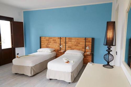 2 letti in una camera d'albergo con parete blu di Agriturismo Dimina a Marinella di Selinunte