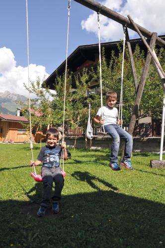 two young boys sitting on swings in a yard at Haus Freispitzblick in Bach