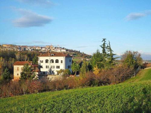 a large white house sitting on top of a green field at Cascina Bringin in Mondovì