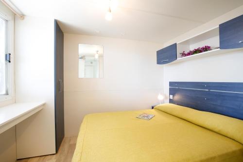 - une chambre avec un lit jaune et une fenêtre dans l'établissement Baia Di Campi, à Vieste