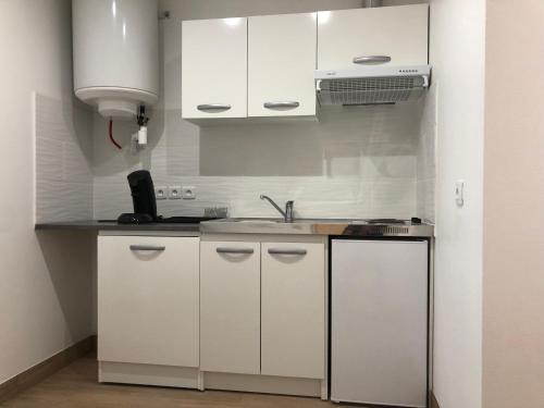 une cuisine avec des armoires blanches et un évier dans l'établissement New Saint Maur-Logement Lovely Flat 32m2, à Paris