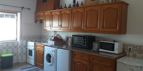 a kitchen with wooden cabinets and a washer and dryer at Azure Guest House in Silveira