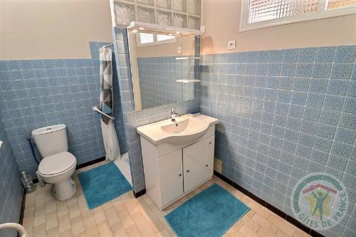 a blue tiled bathroom with a sink and a toilet at Gîte de l'Eclotine in Saint-Théodorit