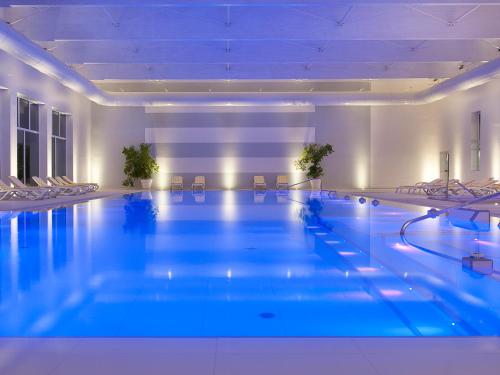 a large swimming pool in a hotel with blue lighting at Hotel Universal Terme in Abano Terme