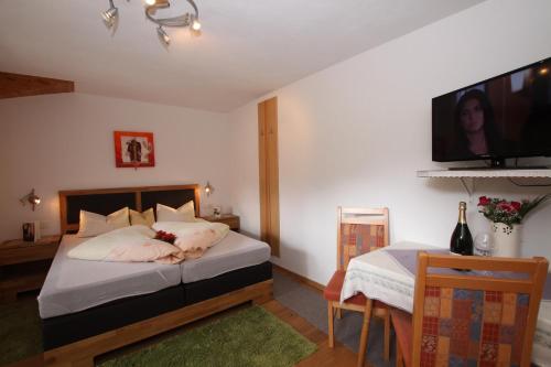 a bedroom with a bed with a tv on the wall at Landhaus Granat in Mayrhofen
