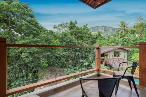 a balcony with two chairs and a view of the forest at Hotel Vila Kebaya in Ilhabela