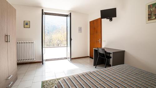 a bedroom with a bed and a desk and a window at albergo bellavista in Re