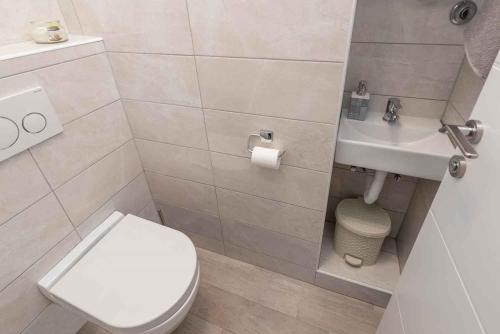 a bathroom with a white toilet and a sink at Sea the Sunset Apartment in Zadar