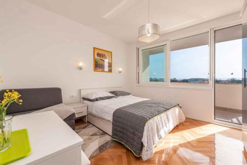 1 dormitorio con cama, sofá y ventanas en Sea the Sunset Apartment, en Zadar