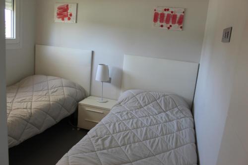 1 dormitorio con 2 camas y mesita de noche con lámpara en Victoria VyB, en Denia