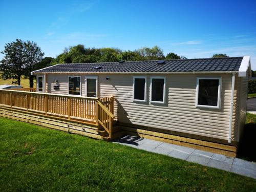 a small white house with a wooden fence at Coed Helen Holiday Park in Caernarfon
