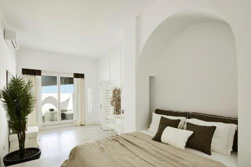 una camera bianca con un letto e una pianta in vaso di Le Blanc Nest Santorini - Family / Couples Luxury House a Mesariá