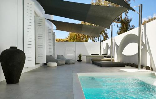 a patio with a swimming pool and a black umbrella at Le Blanc Nest Santorini - Family / Couples Luxury House in Mesaria