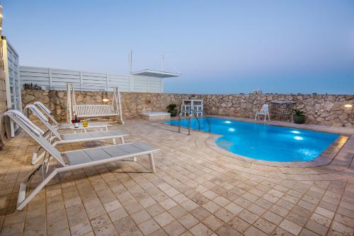 a swimming pool with two chairs and a slide at Nofesh Ba Alon 10 in Rosh Pinna