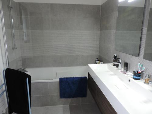 y baño con bañera, lavabo y espejo. en Jolie maison d’architecte en Chambray-lès-Tours