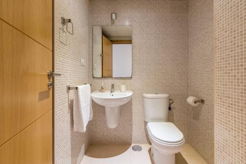 Un baño con inodoro, lavabo y espejo. en COMFORTABLE, CLOSE TO THE BEACH, POOL, NEW, PADDLE, en Rincón de la Victoria