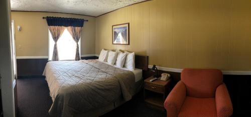um quarto de hotel com uma cama e uma cadeira em Geneva Inn em Geneva