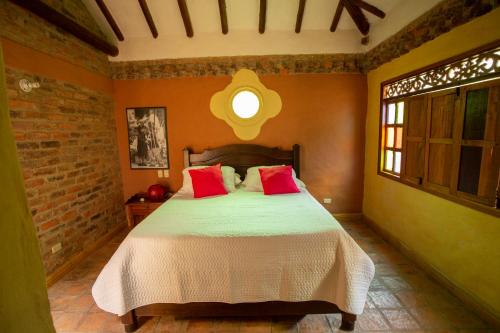 a bedroom with a bed with red pillows at Casas La Primavera in Villa de Leyva