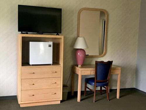 a bedroom with a dresser with a tv and a mirror at Don Q Inn in Dodgeville