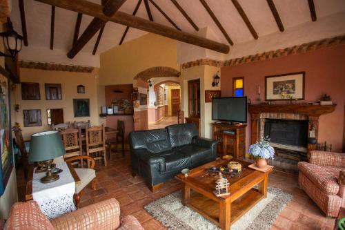 a living room with a leather couch and a fireplace at Casas La Primavera in Villa de Leyva