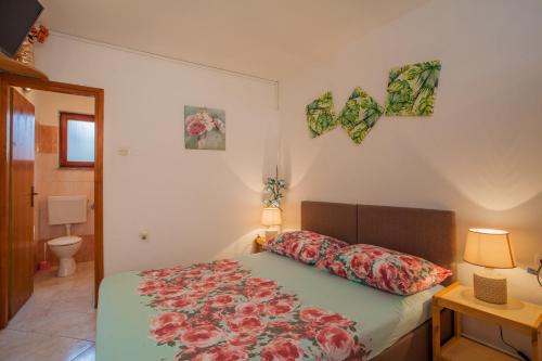 - une chambre dotée d'un lit avec un couvre-lit floral dans l'établissement Rooms Mužić, à Cres