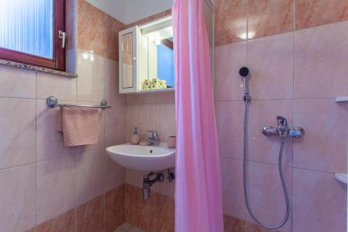 La salle de bains est pourvue d'un lavabo et d'une douche avec rideau de douche. dans l'établissement Rooms Mužić, à Cres