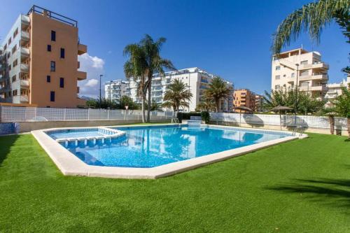 a swimming pool with green grass and buildings at Estudio en primera linea de playa in Daimuz