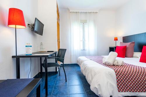 a hotel room with a bed and a desk and a table at Elcano in Málaga