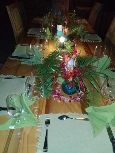 a wooden table with a table set with glasses and a centerpiece at Hotel Rio Celeste Finca L´ Etoile Celeste in El Achiote