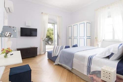 a white bedroom with a bed and a tv at Dimora Cummà Marì in Vieste